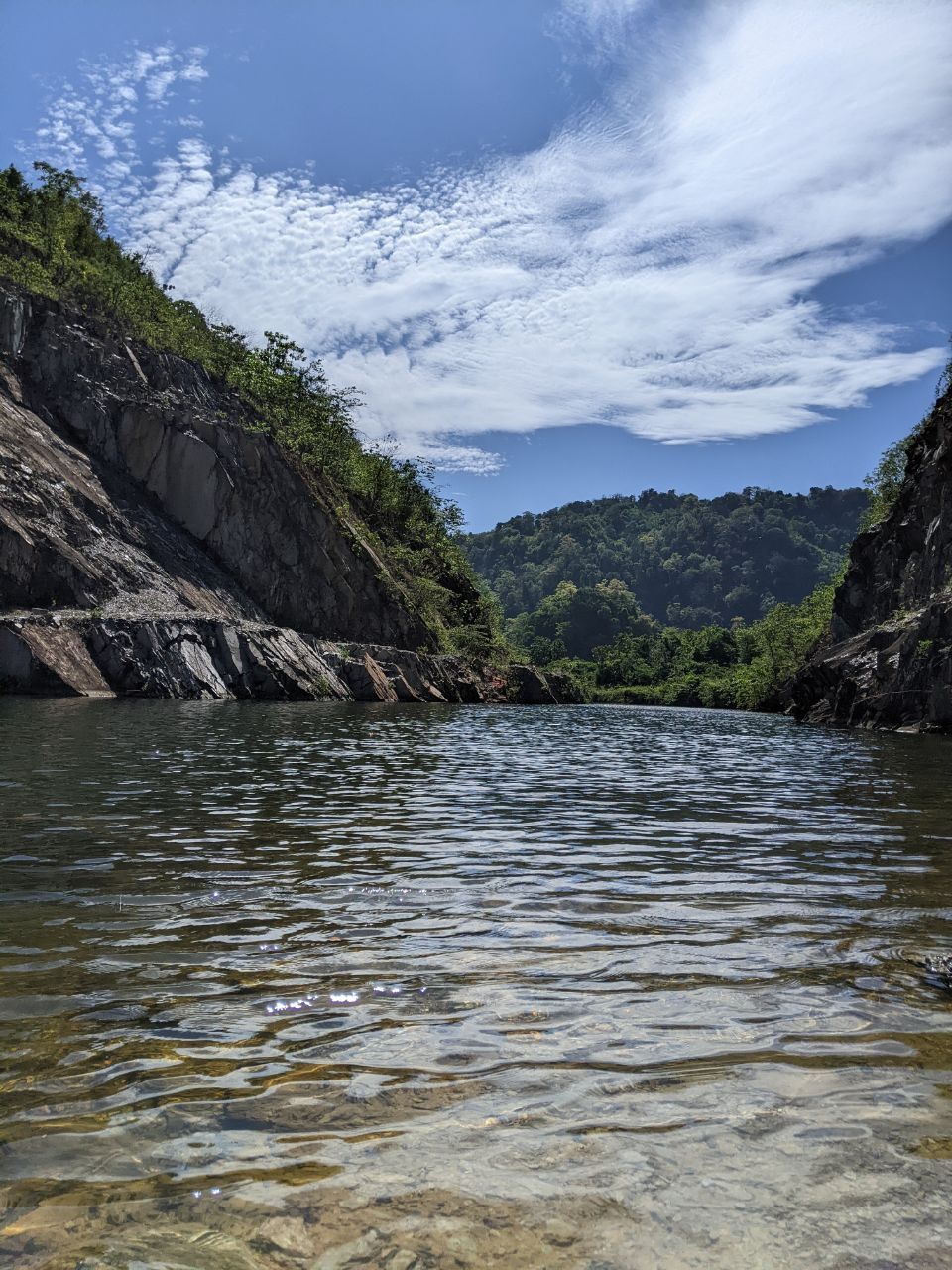 A sunny day at a river. There are rocks formations and a jungle.